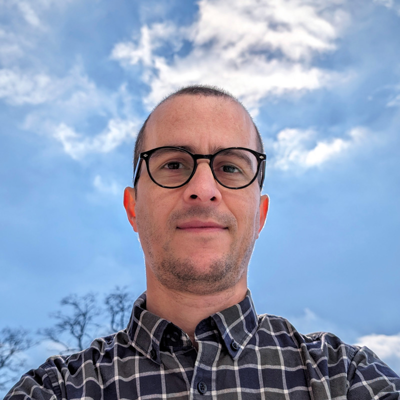 Picture of myself. I am a white male with a shaved head, dark-rimmed black glasses, and a short beard.